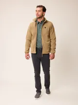 Campera de polar color beige con cierre frontal completo y cuello alto. Presenta un bolsillo en el pecho con cierre y detalle de parche con logo. El diseño combina paneles de tejido polar con detalles en tejido técnico en la zona del pecho.