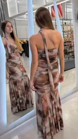 Vestido largo strapless con diseño estampado estilo abstracto en tonos marrones y beige, con detalle de bufanda o lazo al cuello del mismo género y corte sirena con caída fluida.