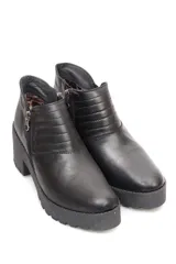 Botín negro de cuero con cierre metálico lateral, costuras decorativas y suela track con plataforma.