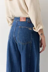 Pantalón de jean azul de tiro alto y corte wide leg súper amplio, con diseño de perneras ancha y terminación desmechada en el ruedo.