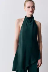Top de cuello halter color verde oscuro, con escote drapeado, manga sisa y bajo asimétrico. Cierre en la espalda.