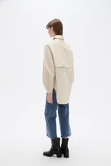 Campera marrón de manga larga confeccionada en algodón, con cuello camisero, cierre frontal con botones a presión y puños elásticos fruncidos.