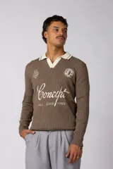 Sweater de punto acanalado en color marrón, con cuello polo en contraste color crema. Presenta diseño estampado con tipografía cursiva y logotipos circulares en el pecho.