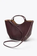 Bolso de mano tipo mini city, color borgoña, con pespuntes en contraste. Presenta asa de mano y asa bandolera extraíble. Incluye una bolsa interior extraíble con cierre de cremallera.