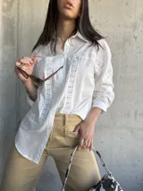 Camisa blanca de manga larga con detalles de encaje en el frente y en los puños.