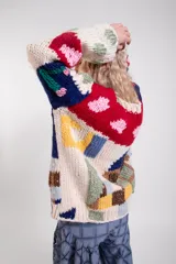 Sweater tejido a mano de lana merino, de diseño holgado con cuello redondo y mangas largas, con un colorido patrón de intarsias que representa escenas de paisajes con casas, cactus y flores.