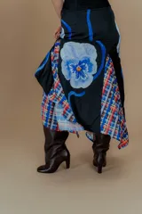 Falda larga de seda negra con estampado floral azul y detalles de tela escocesa en el ruedo.