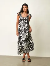 Vestido midi negro con estampado gráfico en blanco, de corte amplio y escote redondo con tirantes anudados en los hombros.
