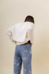Pantalón de jean de corte recto y relajado, con tiro medio-alto. Presenta un estampado floral sutil en tonos claros sobre la base de denim azul y cuenta con interior forrado para mayor abrigo.