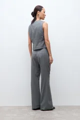 Pantalón sastrero de corte recto y tiro medio, confeccionado en tela con estampado de microcuadros en tonos grises. Presenta bolsillos laterales y cierre frontal con botón.