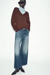 Jeans de tiro bajo, corte recto y largo completo (full length), color azul medio con efecto desgastado y lavado. Modelo de cinco bolsillos con cierre frontal de botones.