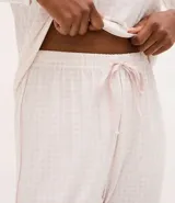 Pantalón de pijama tipo jogger, color blanco con estampado de cuadros sutiles. Presenta cintura elástica con lazo de ajuste y puños elásticos en los tobillos, confeccionado en tejido suave con tacto aterciopelado.