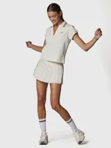 Falda tipo skort con diseño plisado, cintura alta elástica con detalle de rayas horizontales en contraste. Incluye short integrado con bolsillo funcional, confeccionada en tejido técnico de secado rápido.