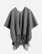 Poncho o capa de tejido grueso color gris liso, con cuello redondo y terminación de flecos largos en el ruedo inferior.