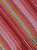 Chal o bufanda de tejido de punto con patrón de zigzag multicolor en franjas verticales, con flecos en los bordes.