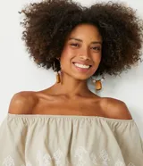 Blusa color beige de hombros descubiertos con volados y bordado floral en el busto.