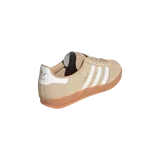 Championes Adidas Gazelle Indoor de gamuza en color beige, con las icónicas tres tiras blancas en los laterales, detalle en el talón de color blanco y suela translúcida de goma caramelo.