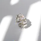 Anillo plateado con cristales ovalados engarzados y diseño infinito.