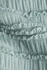 Blusa sin mangas de punto con textura arrugada, escote bote y diseño entallado con peplum y volados decorativos.