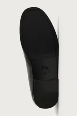 Mocasín de cuero negro con diseño liso, detalle de bordón en el empeine, horma redonda y suela ultrafina.
