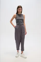 Pantalon de corte relajado, color gris, con cintura elástica y cordón ajustable. Presenta bolsillos frontales tipo parche y puños elásticos en los tobillos.