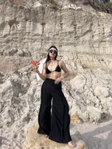 Pantalón negro de tiro alto, corte ancho y fluido, con cintura elástica.