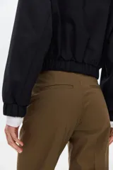 Pantalón cigarette color marrón, confeccionado en tejido elástico, con tiro estándar, bolsillos al bies y piernas ajustadas con raya marcada.