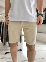 Bermuda de jean corte skinny en color beige, con diseño clásico de cinco bolsillos y cierre frontal con botón y cremallera.
