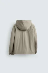 Parka de tejido técnico con acabado engomado, cuello subido y capucha ajustable. Presenta cierre frontal con cremallera oculta bajo solapa con botones a presión, bolsillos laterales de vivo y mangas largas con puños ajustables.