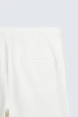 Bermuda negra de corte recto, con cintura elástica ajustable mediante cordón, pliegues frontales y bolsillos de vivo en la espalda. El bajo tiene un dobladillo vuelto.