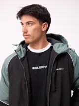 Campera Rusty con capucha, diseño bicolor en negro y verde militar. Presenta cierre frontal, puños elásticos y logo de la marca bordado en el pecho.