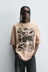 Camiseta de algodón color beige, corte relaxed fit, con cuello redondo y manga corta. Presenta un estampado gráfico grande en negro con motivos variados como una estación de servicio antigua, un caballo alado, una polilla, un pájaro y el texto "RUSTED ROSE".