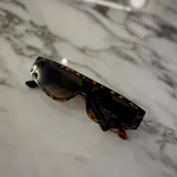 Lentes de sol rectangulares con marco de carey y lentes degradadas de marrón a transparente.