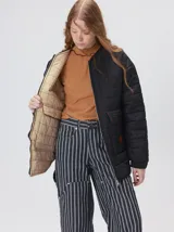 Campera reversible capitoneada con cierre frontal. Un lado es de color negro y el otro es de color beige, ambos con diseño acolchado. Cuenta con cuello redondo, mangas largas y bolsillos laterales.