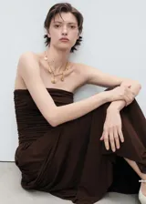 Vestido largo color marrón, con diseño palabra de honor y cuerpo entallado con detalle fruncido en la cintura. La falda presenta una caída fluida y amplia.