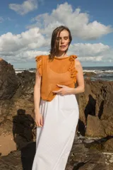 Musculosa tejida en punto calado, color violeta, con diseño sin mangas y detalle de flecos en los hombros.