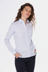 Camisa de tejido Oxford lisa y color blanco, con cuello camisero, cierre frontal de botones y mangas largas con puños abotonados.