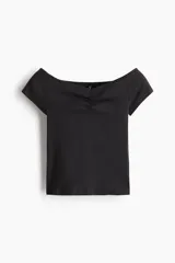 Top negro de manga corta, confeccionado en tejido acanalado, con escote tipo bote que deja los hombros descubiertos y detalle fruncido en el centro del busto.