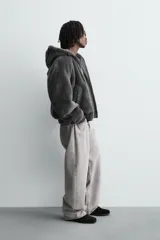 Cazadora bomber de corte relajado confeccionada en tejido efecto piel con acabado desgastado. Presenta capucha ajustable, cierre frontal con cremallera de doble dirección, bolsillos laterales y puños y bajo con rib elástico.