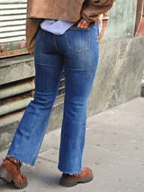 Jean azul de corte flare, con cintura alta y ruedo deshilachado.