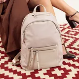 Mochila color beige, combinada con tela tipo impermeable y detalles en simil cuero. Tiene gran tamaño, asas combinadas, bolsillos al frente y compartimiento para notebook de 15".