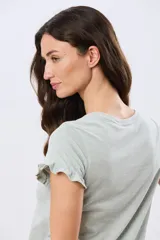 Remera de algodón color verde menta, con escote redondo y mangas corta con detalles de volados sutiles en los puños.