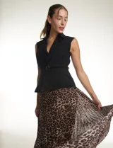 Vestido midi de estilo sastre con cuerpo tipo chaleco negro de cuello solapa y escote en V, con cierre lateral y cinturón con hebilla. La falda es plisada con estampado animal print y cuenta con forro interno.