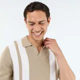Remera de punto de manga corta en color beige con franjas verticales blancas, diseño con cuello tipo polo sin botones.