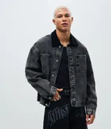 Campera trucker de corte boxy en denim color gris lavado. Presenta cuello de terciopelo negro, cierre frontal con botones metálicos y dos bolsillos frontales con solapa.