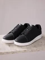 Championes negros de cuero sintético con suela blanca de goma.