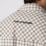 Camisa de manga corta de popelina con patrón a cuadros, calce boxy y largo a la cintura, con bolsillos y canesú cortados en diagonal.