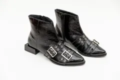 Botas cortas de cuero charol color negro, con aplique de hebillas con ojalillos y cierre lateral. Taco cuadrado bajo.