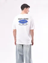 Remera blanca de corte holgado con estampado pequeño en el pecho que dice 'SIGHT+SOUND' y símbolos de audio.