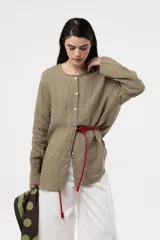 Camisa de lino color beige, de calce relajado, cuello redondo y cierre frontal de botones.